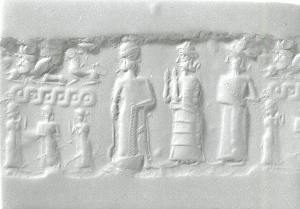 Photo of an ancient Mitanni cylinder seal (ca. 1500–1350 BCE) carved in stone, showing engraved figures including a chariot and horses, used to make impressions in clay for administrative or ceremonial purposes.