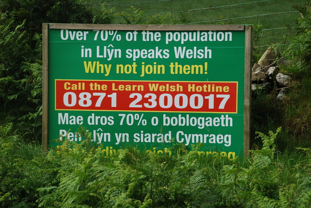 Public sign reading “Defnyddiwch eich Cymraeg – Use your Welsh” encouraging the use of the Welsh language.