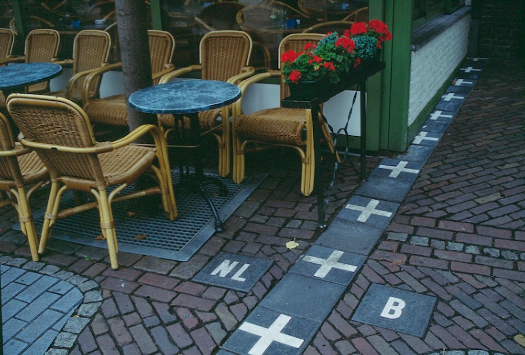 Photograph of a café in Baarle-Nassau, Netherlands, showing the international border with Belgium marked on the pavement, illustrating how the Belgium-Netherlands boundary runs through everyday spaces in this unusually interwoven enclave region.