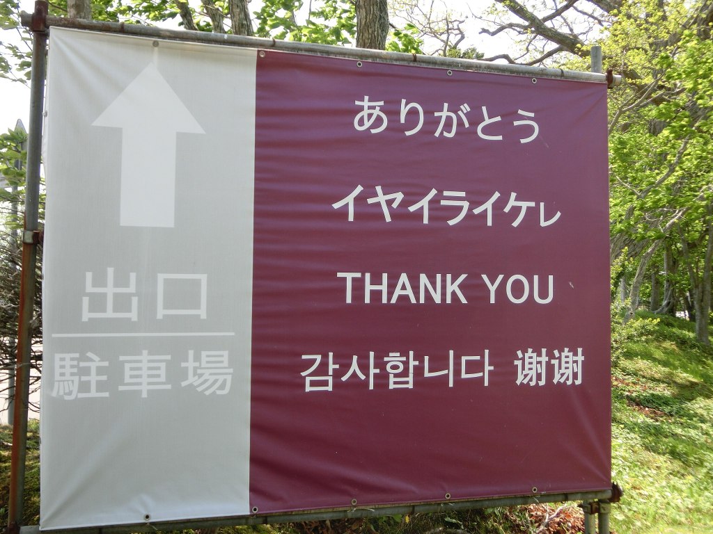 Multilingual sign at the Ainu Museum in Shiraoi displaying Ainu alongside Japanese, English, Korean, and Chinese.